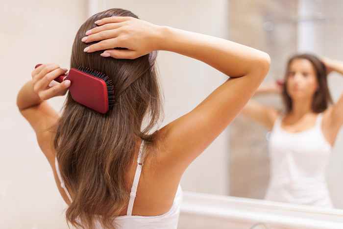 mulher-jovem-escovando-um-cabelo-saudavel-na-frente-de-um-espelho